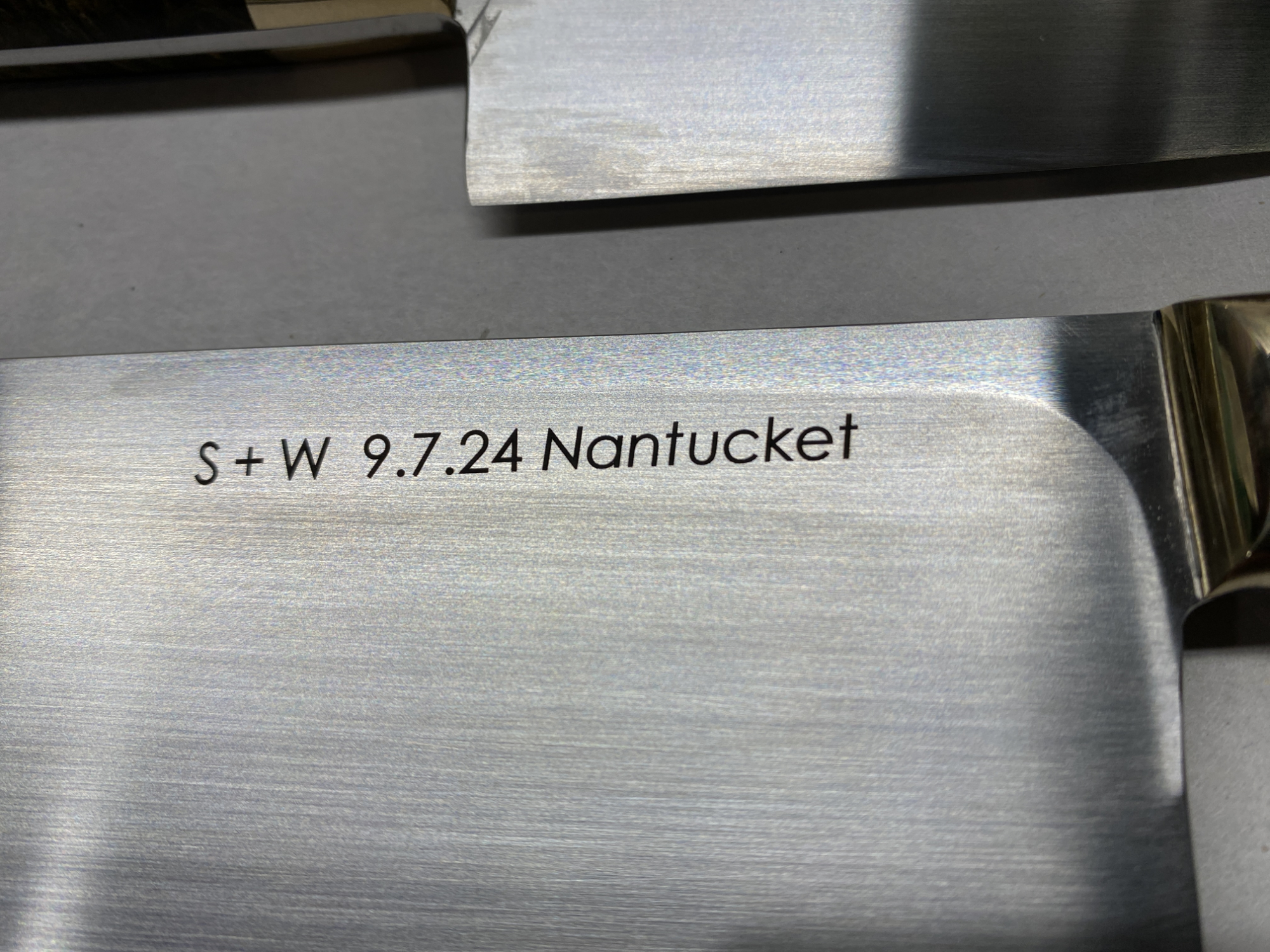 Closeup of dark laser engraving mark on stainless custom knife